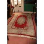 A heavy Chinese Rug, the centre red ground surrounded by a large floral border and similar decorated