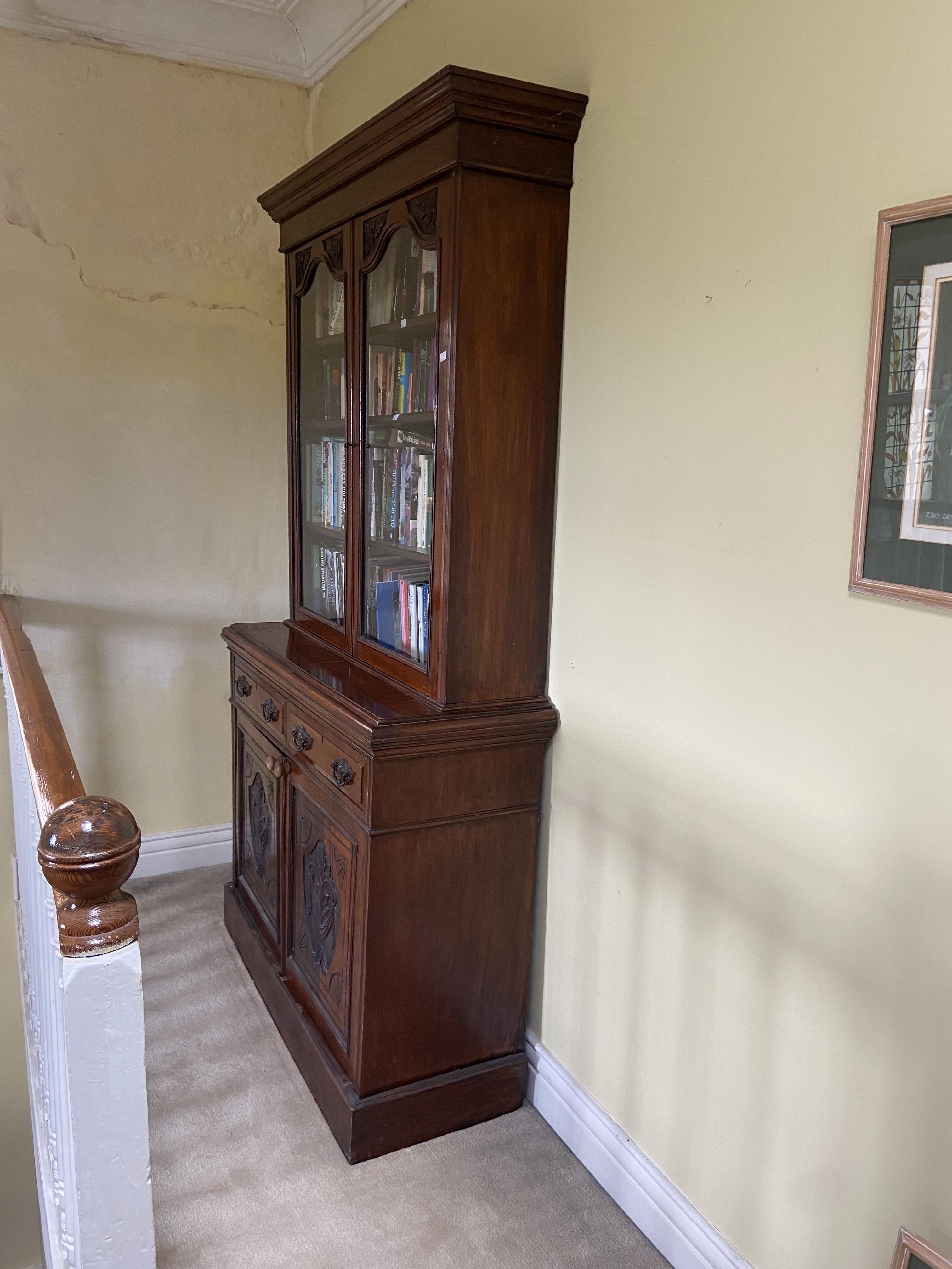 An Edwardian walnut Bookcase, with two upper glazed doors and two frieze drawers above two carved