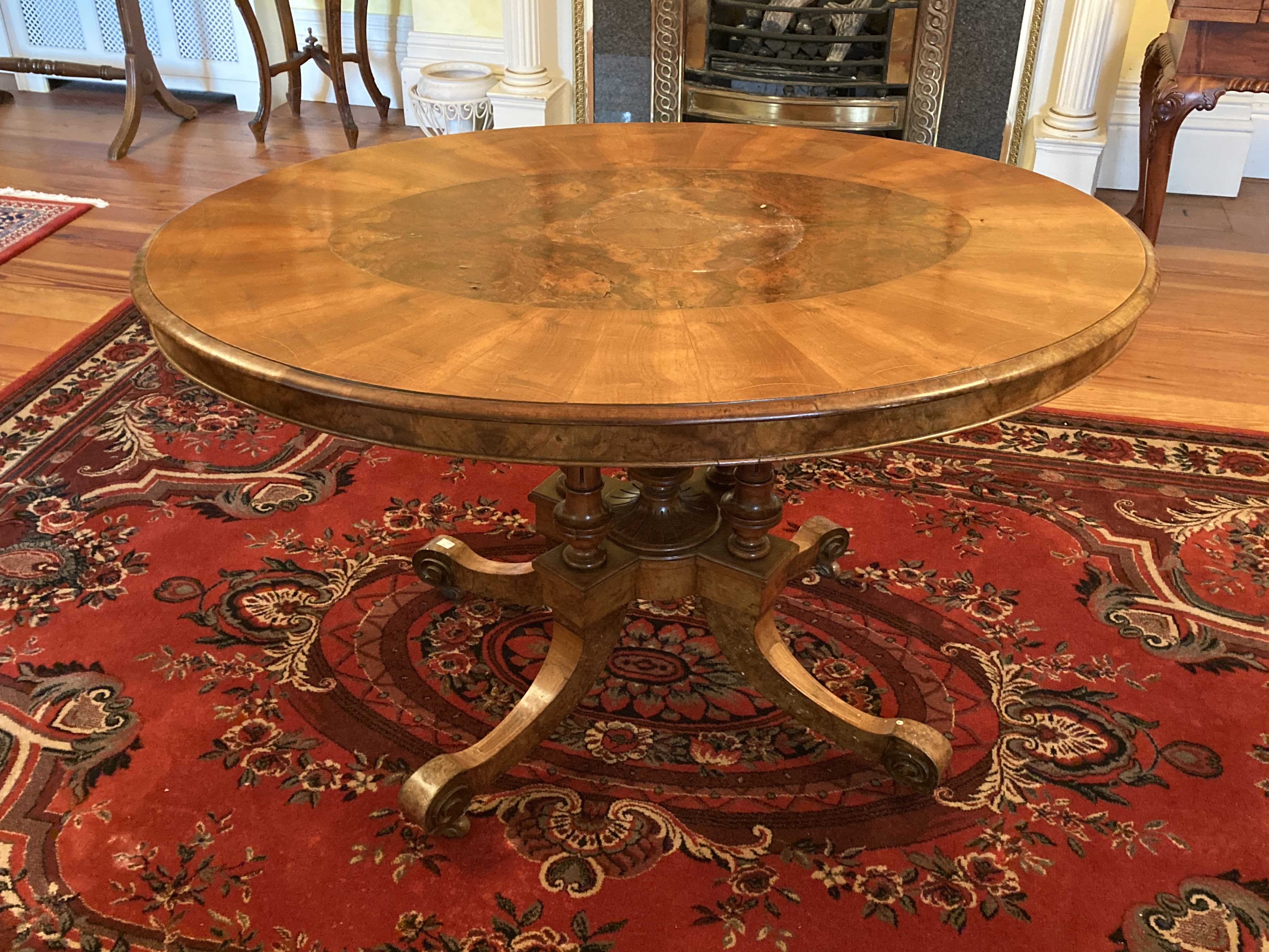 A Victorian oval inlaid walnut Loo Table, on four fluted and turned stems on a quadruple pod with