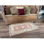 A small Turkish Rug, the iron red ground with three medallions inside an ivory border, 59'' x