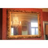 A large carved giltwood Mirror of rectangular form, the frame profusely caved with scrolling