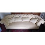 A Victorian Settee, of low proportions, covered in cream deep button fabric on ebonised turned feet,