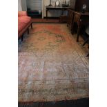A faded wool Carpet, probably Donegal, in the Oriental style, with large central medallion on iron