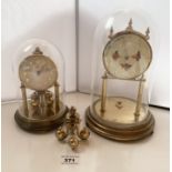 2 glass dome clocks, one with flowered face 9.5” (24cm) high, (needs attention) and one named