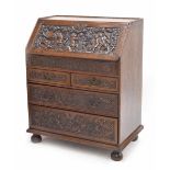 Early 18th century carved oak bureau, the fall front deeply carved with bacchanalian putti amidst