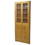 Modern light oak corner cupboard, the upper glazed cupboard doors enclosing shelved interior, the