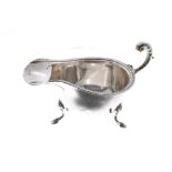 George VI silver cream boat, with leaf capped C scroll handle, raised on three hoof feet, maker S