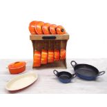 Le Creuset - set of six sauce pans with lids, largest 22cm, on a wooden display rack bearing Le