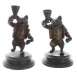 Pair of painted novelty bronze 'drunken bear' candlesticks, mounted upon circular metal plinths,