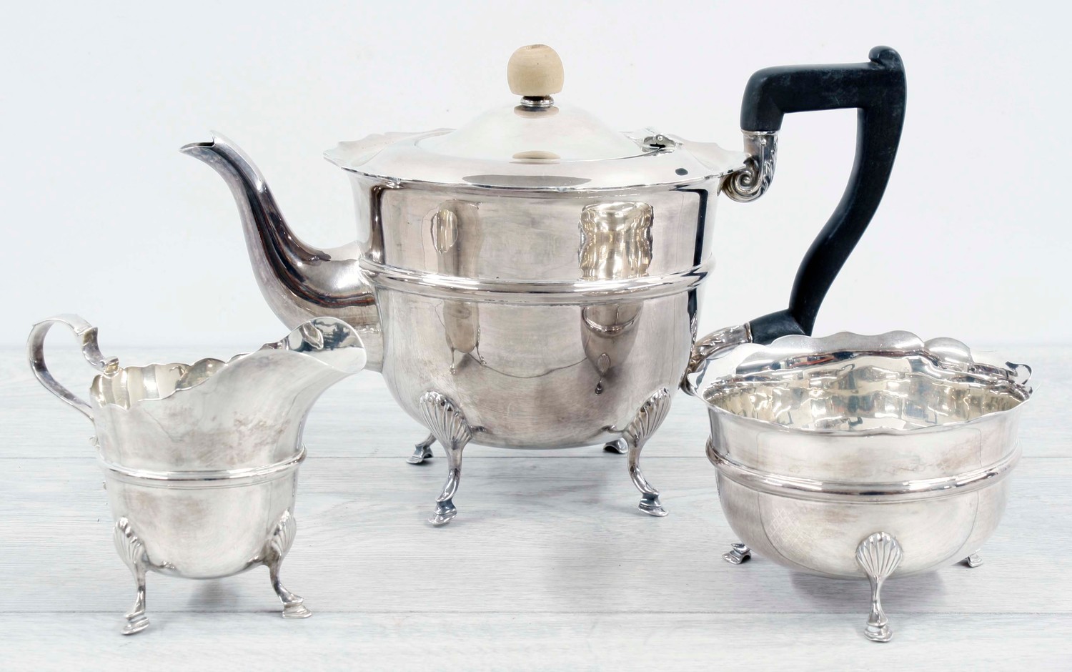 Edward VII three piece silver tea set, with card cut rims raised on hoof feet, the teapot 5" high,