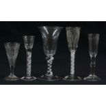 Three antique drinking glasses with air-twist stems, one example with a funnel engraved bowl and