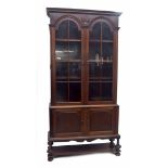 Tall mahogany bookcase, the moulded cornice over two arched panelled glazed cabinet doors upon a