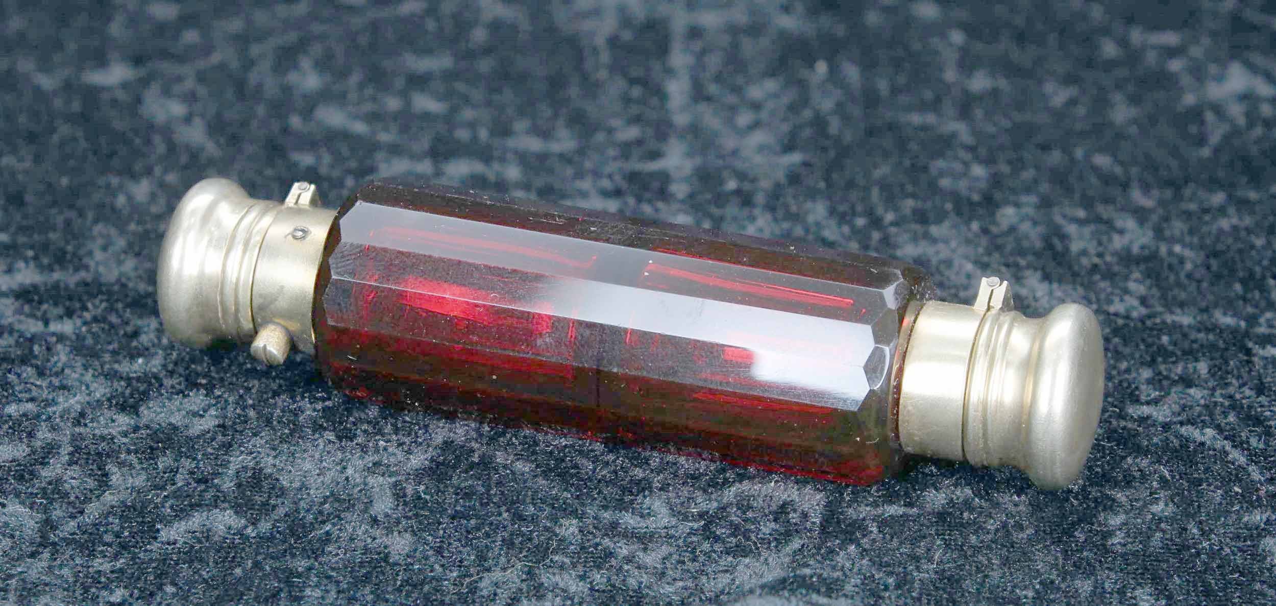 Victorian cranberry glass double-ended scent bottle, the facet cut bottle with gilded white metal