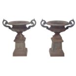 Pair of large cast iron twin-handled campagna urns upon square pedestals, 38.5" high, 35" wide