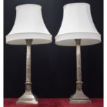 Large pair of silvered Corinthian column table lamps upon square stepped bases, with white shades,