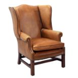 Georgian style tan leather studded upholstered wing armchair, upon square supports united by