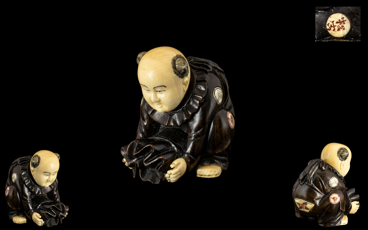 A Fine Quality Small Japanese Ivory and Carved Wood Netsuke Depicting a Small Boy Holding a Sack of