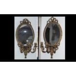 A Matching pair of Victorian Gilded Gesso Candelabra Mirrors of oval shape with a lace bow