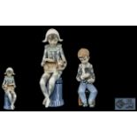 Nao by Lladro Pair of Hand Painted Porcelain Figures. Comprises 1/ Young Boy Harlequin Holding a