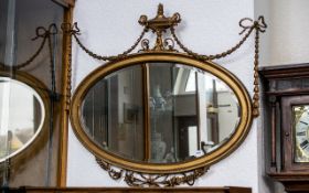 An Adams Style Oval Shaped Gilt Gesso Mirror with fine ribboned swags surmounted by an urn. Damaged.