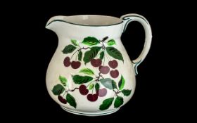 Large Wemyss Pottery Water Jug with handle, decorated with cherries on a white background.