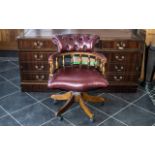 An Oxblood Leather Captain's Chair of typical form with button back. Height 32", widest point 24".