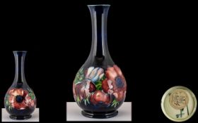 Moorcroft Bottle Vase approx 20.5 cm tall, dark blue with pink Anemone pattern.