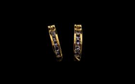 Tanzanite Huggy Hoop Earrings, each hoop, channel set with a row of round cut tanzanites,