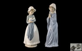 Two Nao Figures, a girl holding a dog and a nun, praying, each 11 inches (27.