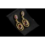 Ruby Drop Earrinngs, each earring comprising two oval cut rubies, of different sizes, the smaller,