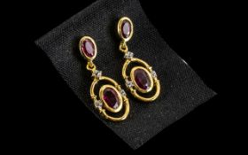Ruby Drop Earrinngs, each earring comprising two oval cut rubies, of different sizes, the smaller,