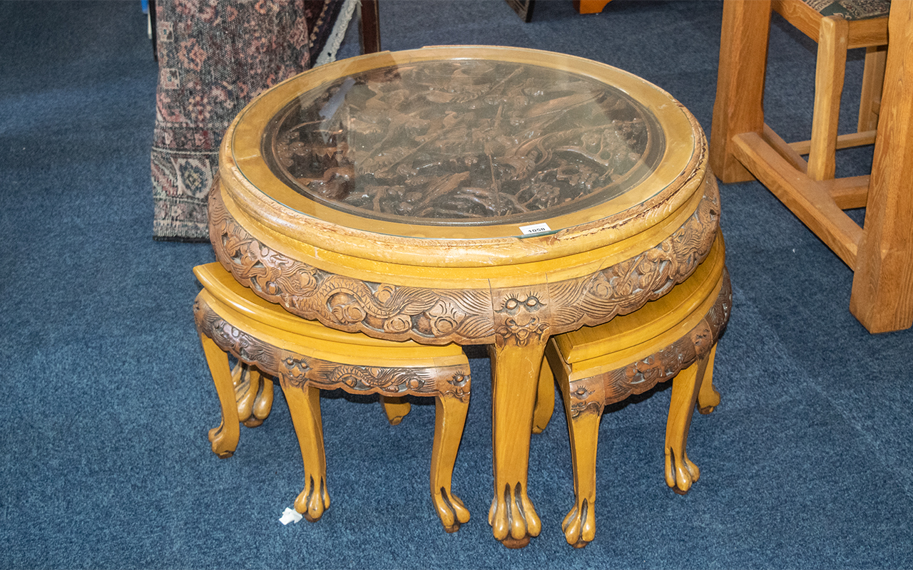 An Oriental Round Circular Nest of Tables of Circular Form, A Glass Top Above a Carved Fighting