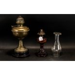 Two Oil Lamps, one on a decorative red and amber glass base,