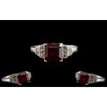 Ruby and Zircon Ring, a square cut, 2.5ct ruby solitaire set to the centre, flanked by round cuts of