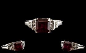Ruby and Zircon Ring, a square cut, 2.5ct ruby solitaire set to the centre, flanked by round cuts of