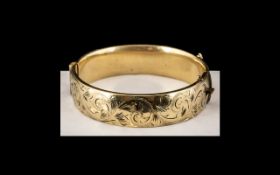 A 9ct Gold Metal Core Hinged Bangle, chaste floral decoration to front,