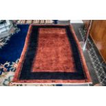 Hand Made Afghanistan Tribal Carpet with an inner blue border, on a burnt orange ground,
