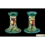 W. Moorcroft Signed Pair of Tube lined Small Candlesticks ' Orchids ' Design on Blue / Green Ground.