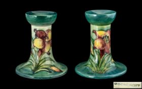 W. Moorcroft Signed Pair of Tube lined Small Candlesticks ' Orchids ' Design on Blue / Green Ground.