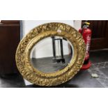 A Circular Bevelled Glass Gilt Framed Mirror with embossed scroll and shell decoration. 26" x 30".