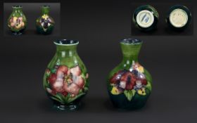 Moorcroft Pair of Tubelined Small Vases 'Orchids' Pattern on a green ground;