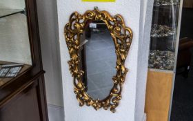 Ornate Gold Painted Mirror, oval shaped with scroll shapes and two winged figures, measures 16''