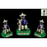 Cricket Interest A Crown Staffordshire Figure of a seated black boy with golf bag,