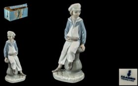 Lladro Figure of Boy on a Capstan, holding a model boat. Approx 9.5" tall, in original box.