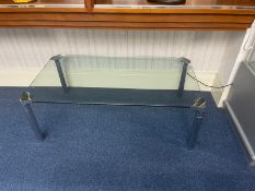 A Contemporary Glass Coffee Table with polished chrome legs and corner decorative detail.