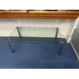 A Contemporary Glass Coffee Table with polished chrome legs and corner decorative detail.