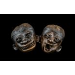 Two Carved Nuts in the form of distorted masks/Faces. Measuring approx 4 by 3.5 inches.