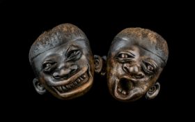 Two Carved Nuts in the form of distorted masks/Faces. Measuring approx 4 by 3.5 inches.