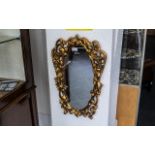 Ornate Gold Painted Mirror, oval shaped with scroll shapes and two winged figures, measures 16''