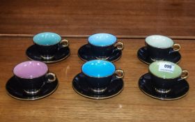 A Set of Six Black Coloured Cups and Saucers with guilt trim and pastel coloured interiors.